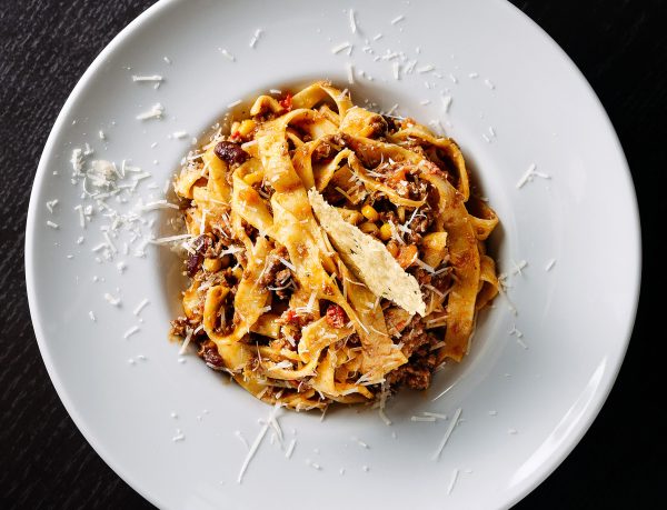 A tasty fettuccine pasta dish topped with grated cheese on a white plate