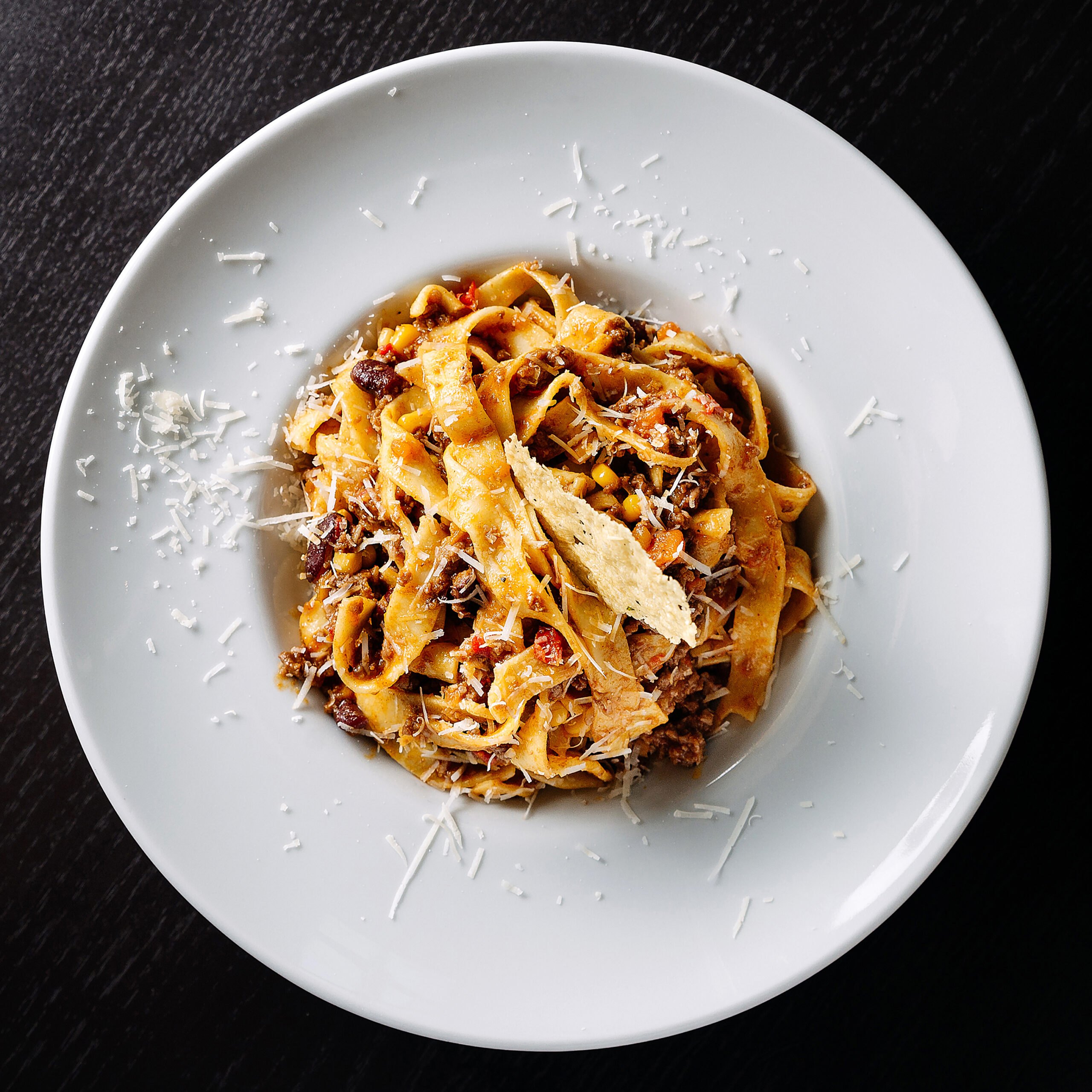 A tasty fettuccine pasta dish topped with grated cheese on a white plate